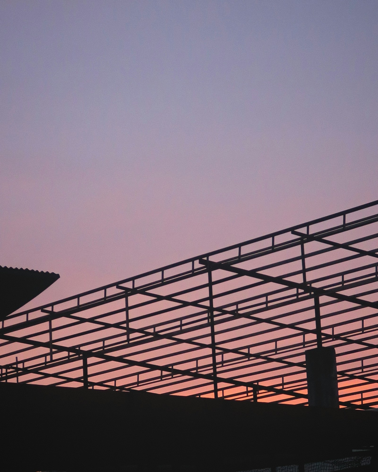 Structural steel roof framing of an industrial building under construction at dusk